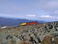 A cogwheel locomotive is pushing a passenger car up.
